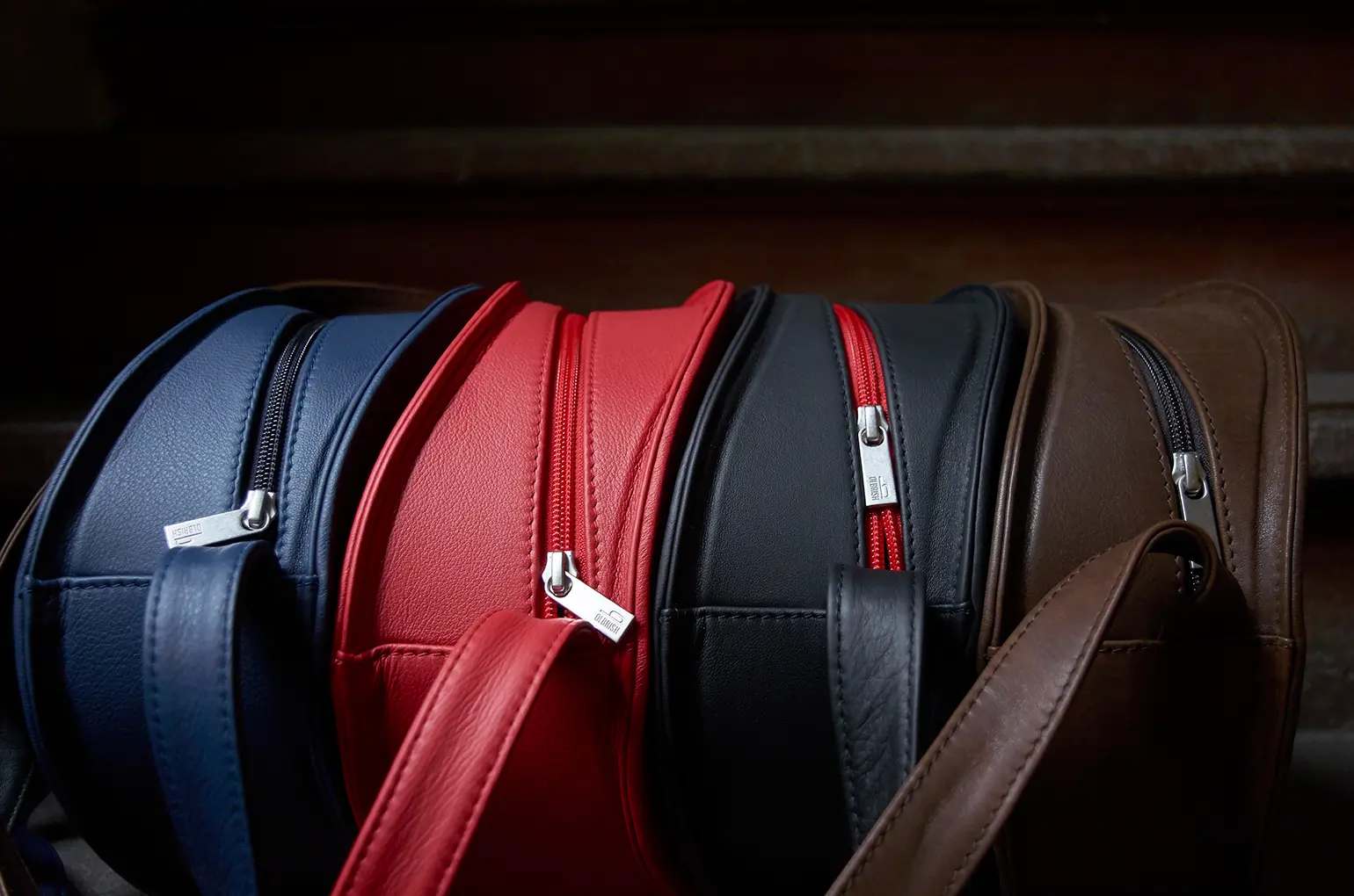 Vier bunte Olbrish Ledertaschen, Modell Charlie, in einer Reihe auf einer Stufe im Treppenhaus