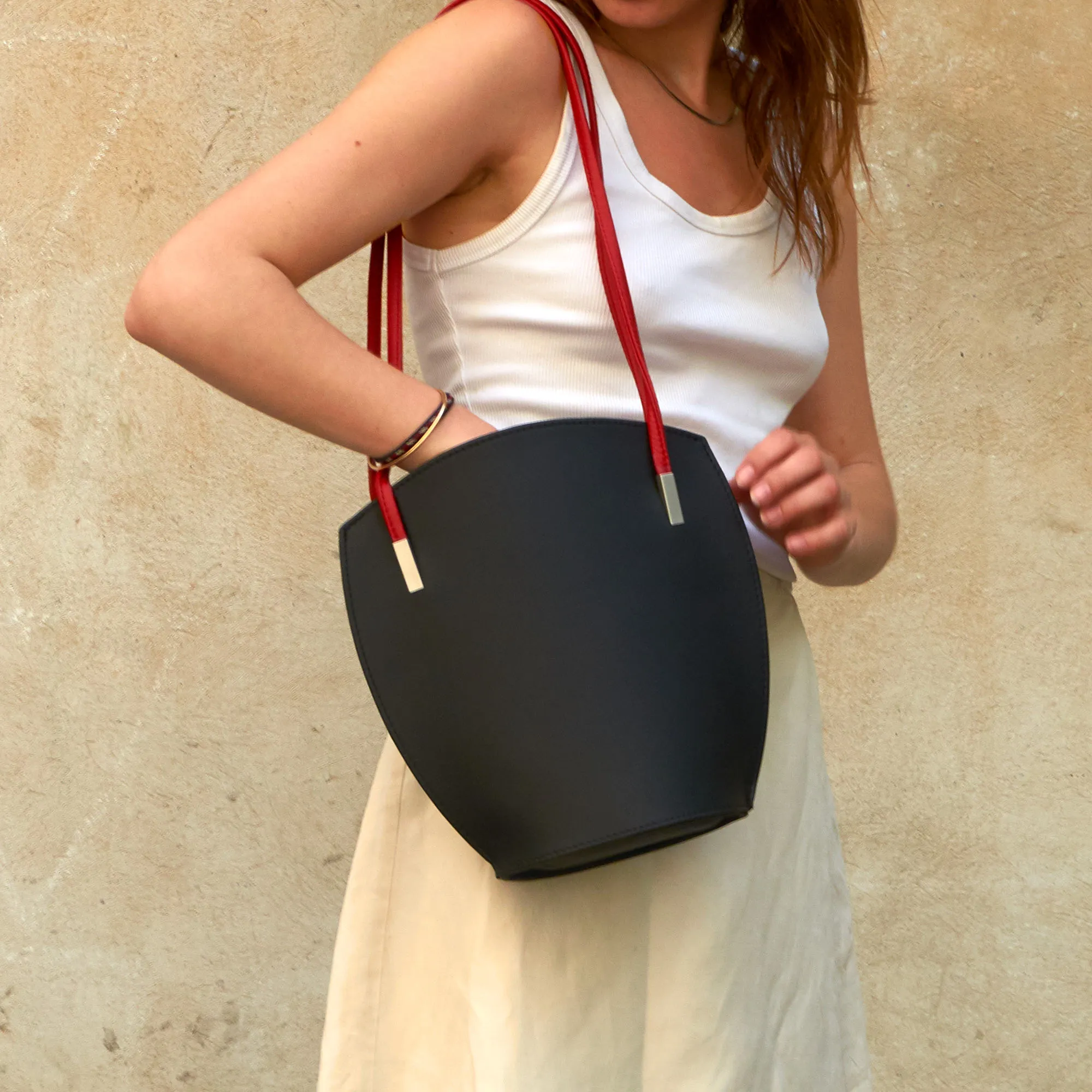 Frau sucht in Olbrish Handtasche Lotus aus schwarzem Nappaleder, mit roten Trageriemen